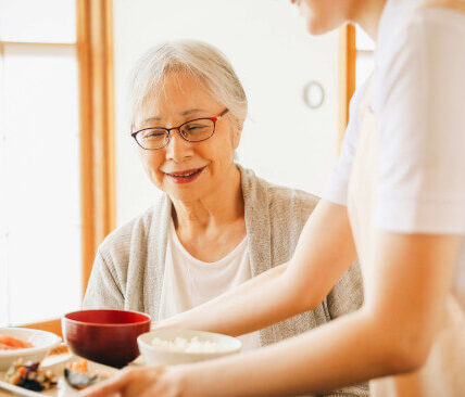 料理を配膳する人とそれを待つ女性
