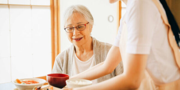 料理を配膳する人とそれを待つ女性