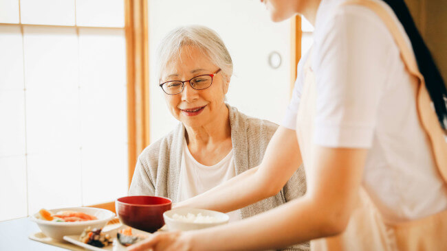 料理を配膳する人とそれを待つ女性